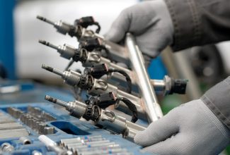Car service. Engine repair. Fuel frame with injectors. Close-up. The car mechanic performs repair work, restores the fuel system of the car.